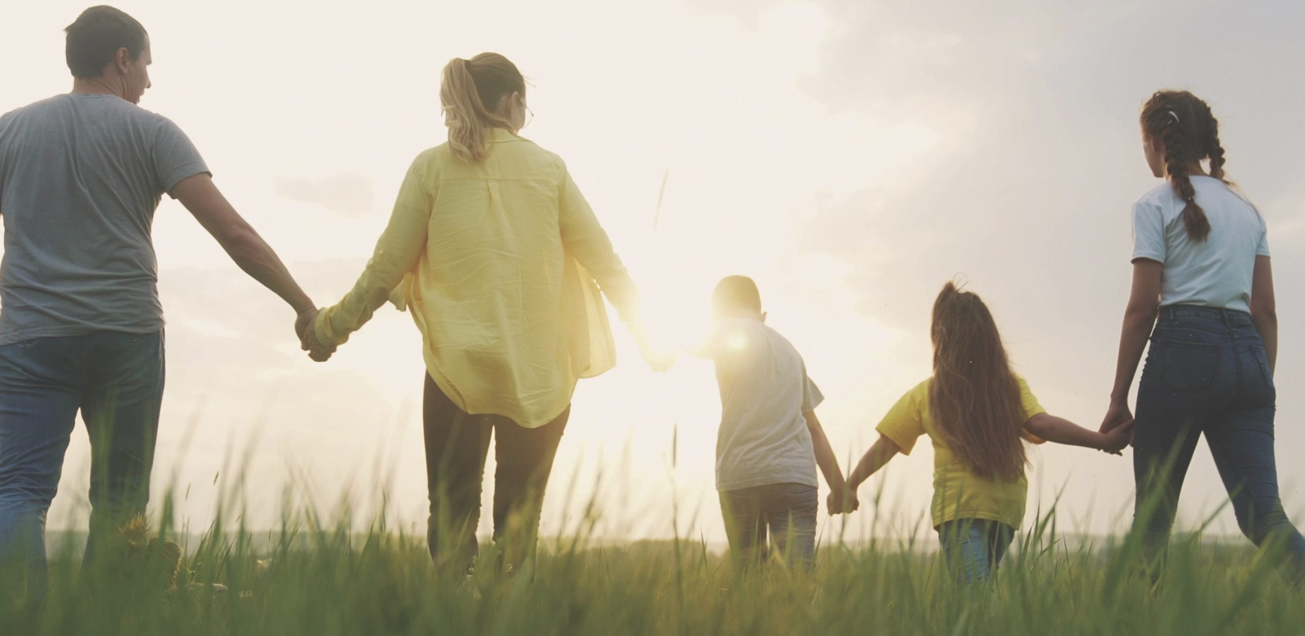 family holding hands and walking at sunset