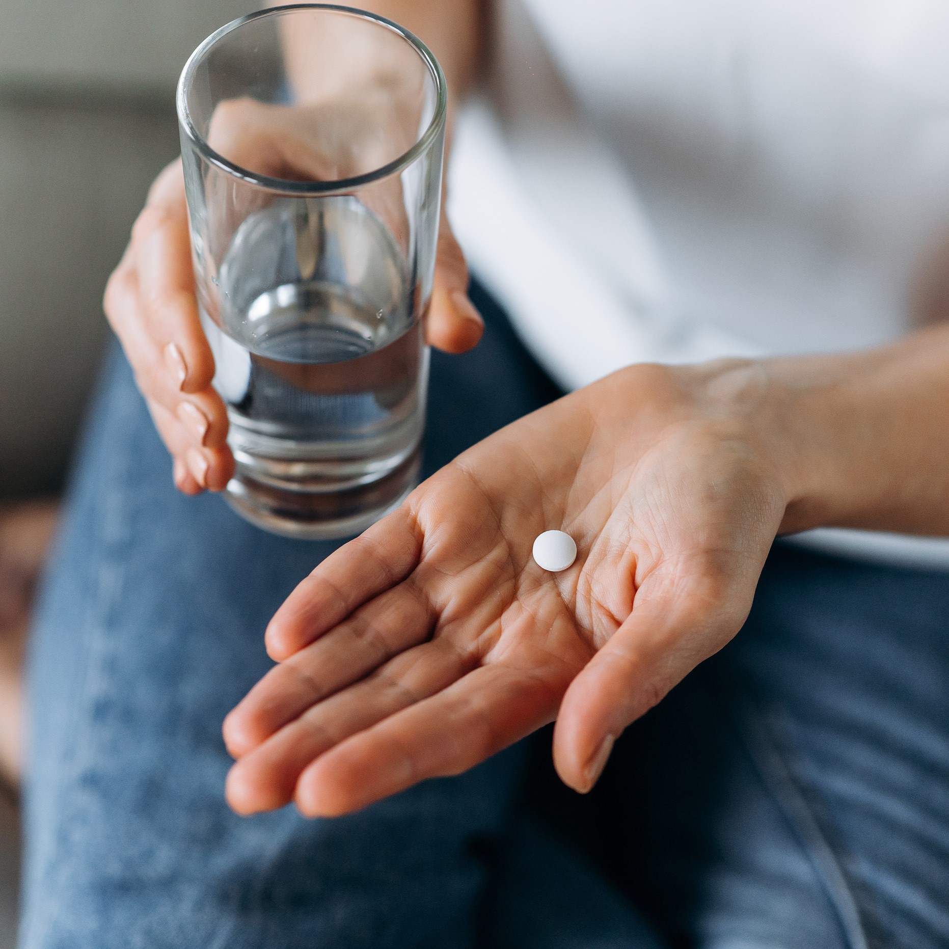 Female hand holding a pill and water