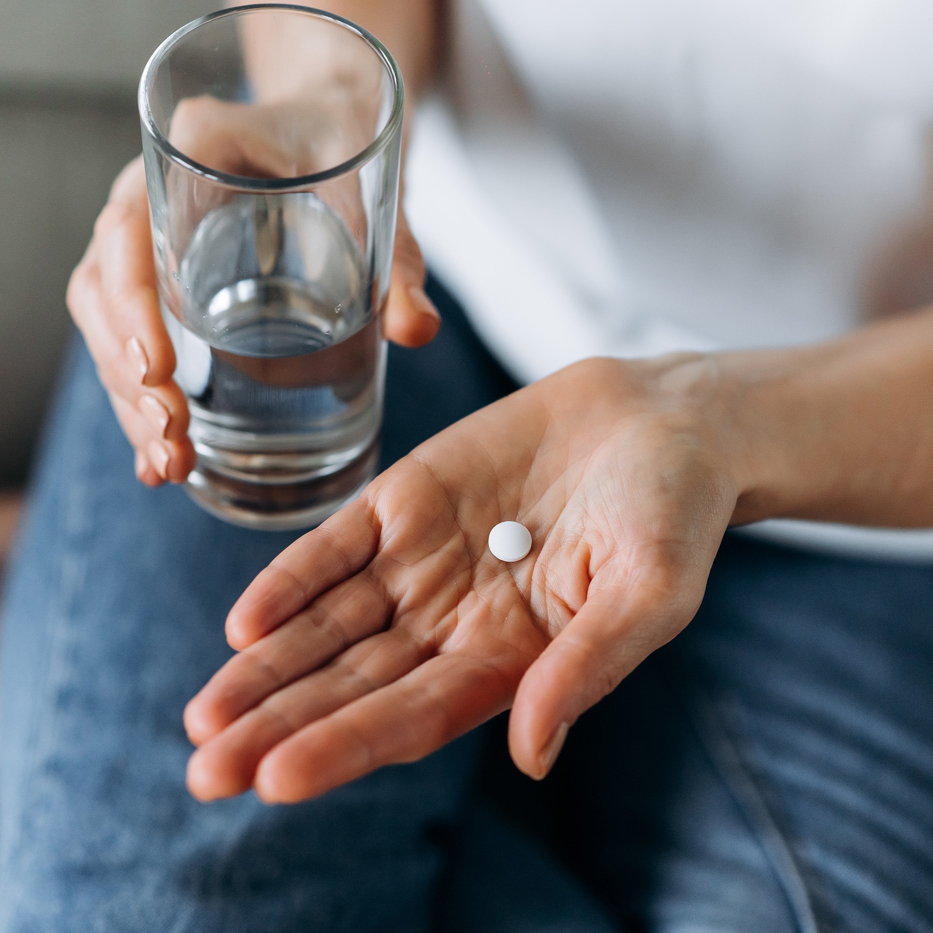 female holding water and a white pill