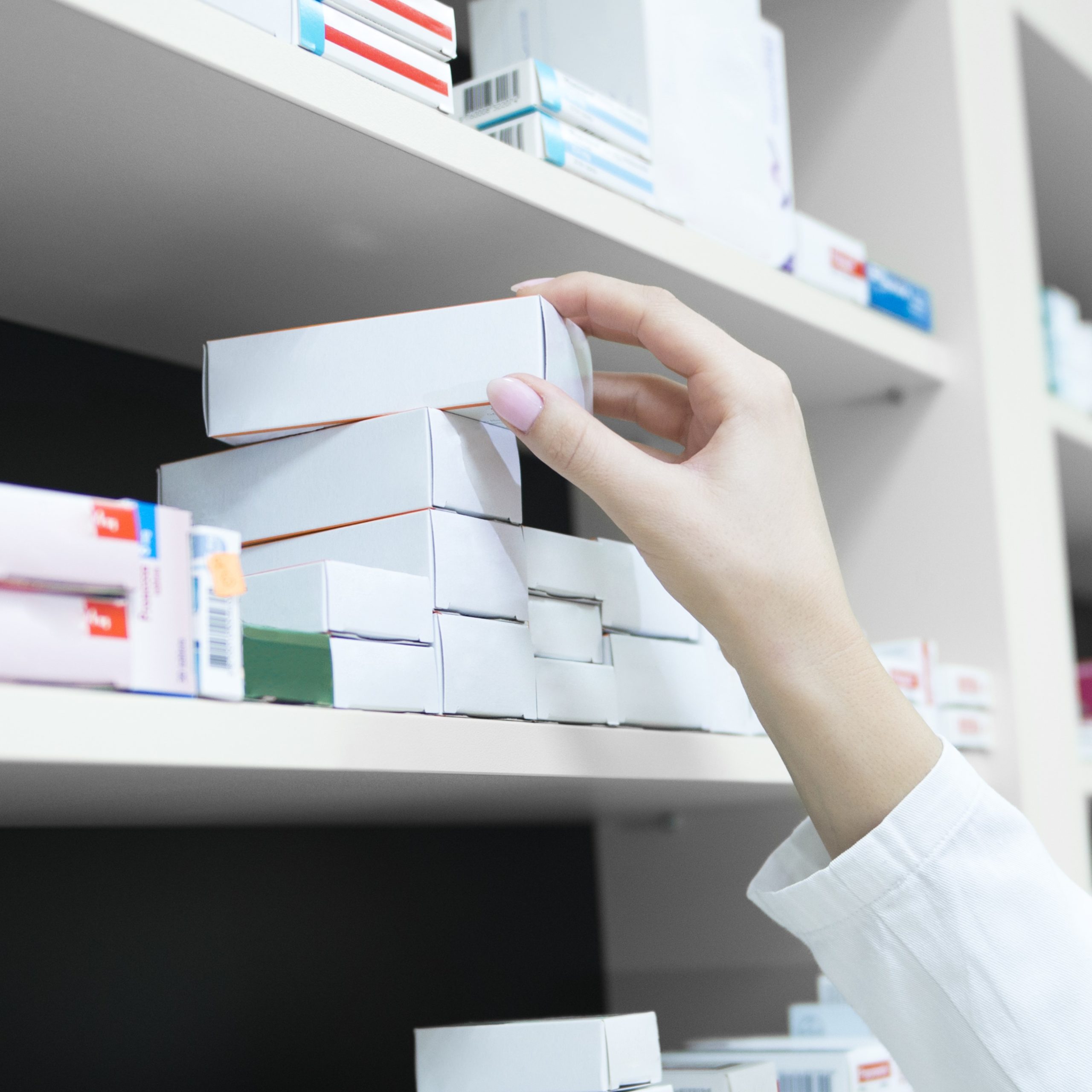 pharmacist grabbing medical box from shelf